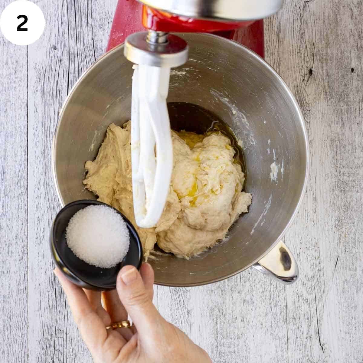 Adding salt to dough in the bowl of a stand mixer.
