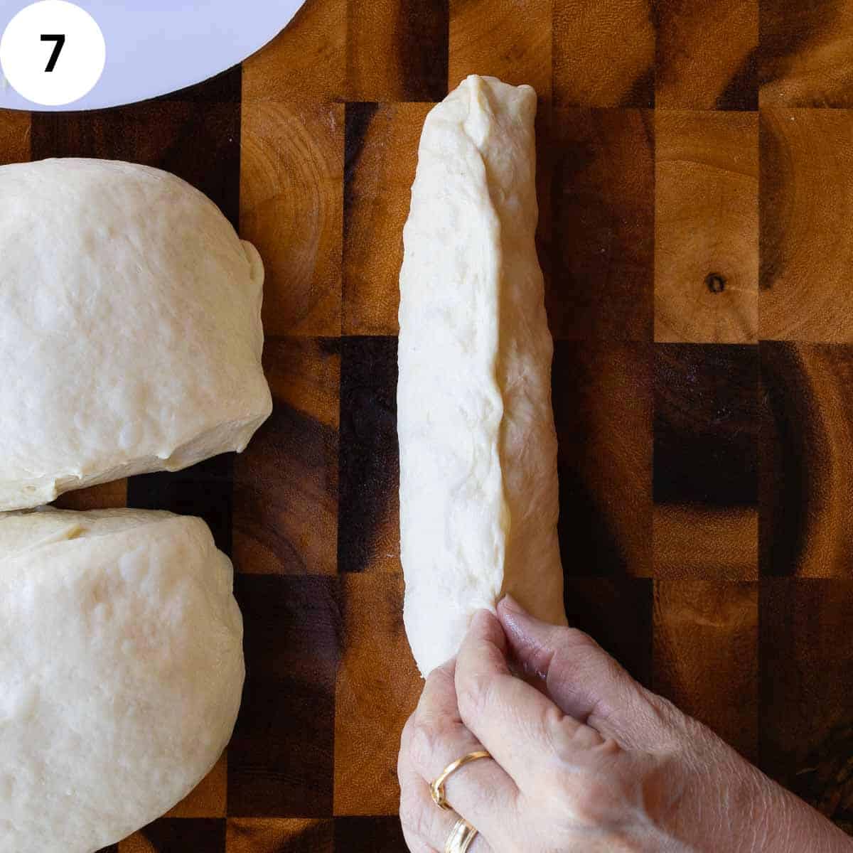 Pinching edges of rolled up bread dough together.