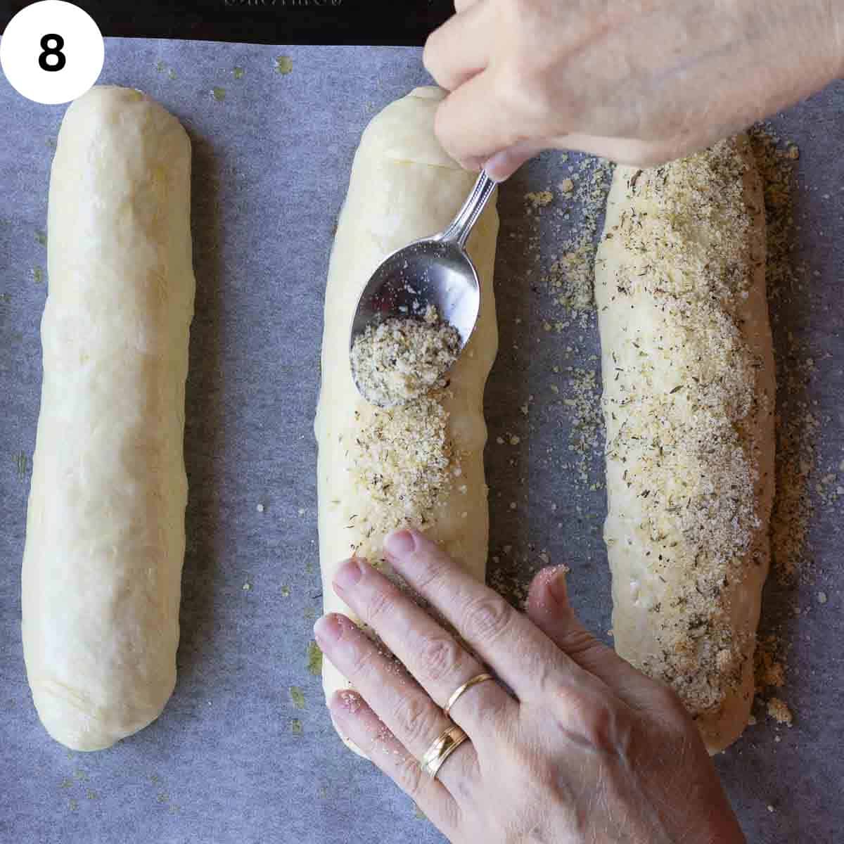 Sprinkling cheese and herb mixture on bread dough loaves.