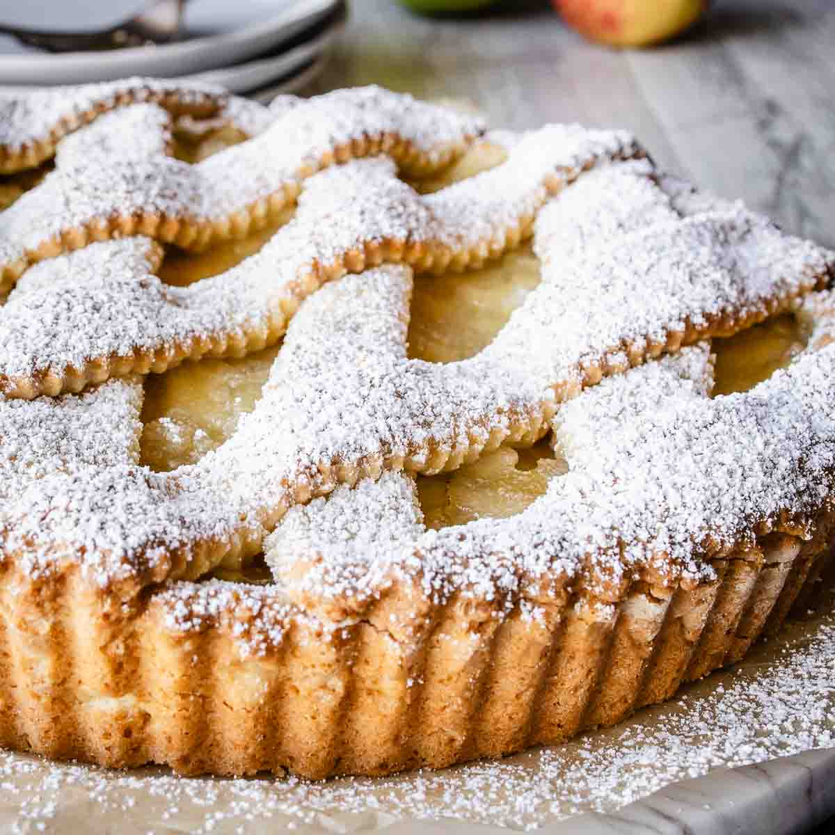 Apple crostata with lattice top crust dusted with powdered sugar.