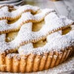 Apple crostata with lattice top crust dusted with powdered sugar.