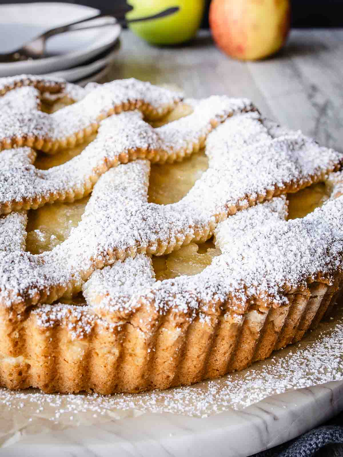 Apple crostata with lattice top crust dusted with powdered sugar.