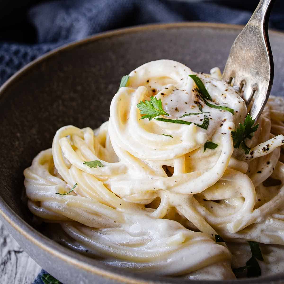 Cream cheese pasta in a bowl being twirled onto a fork.