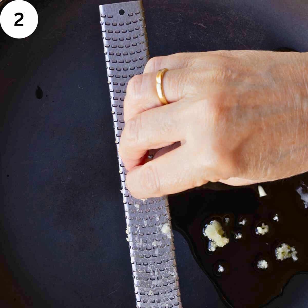 Garlic being grated into a pan.