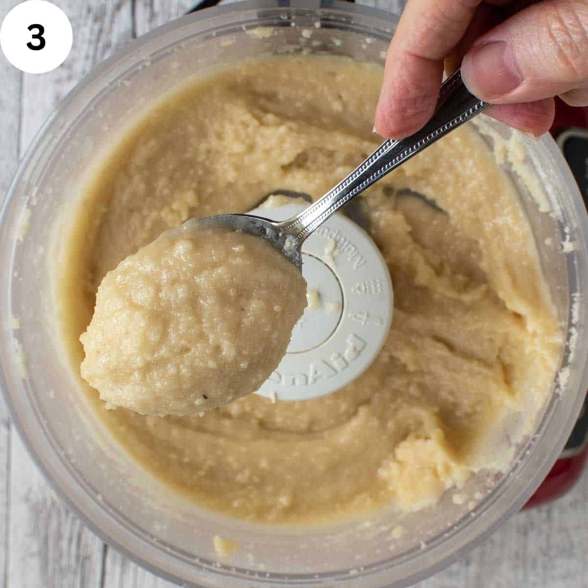 Soft grainy batter scooped up in a teaspoon.