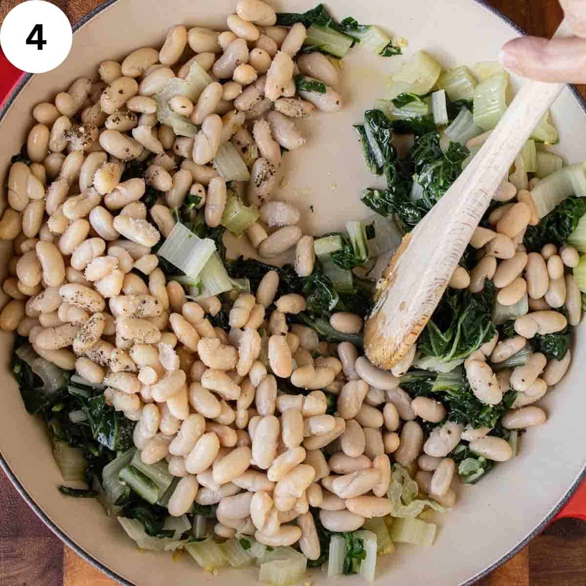 Pan of canned cannellini beans and cooked Swiss chard being stirred.