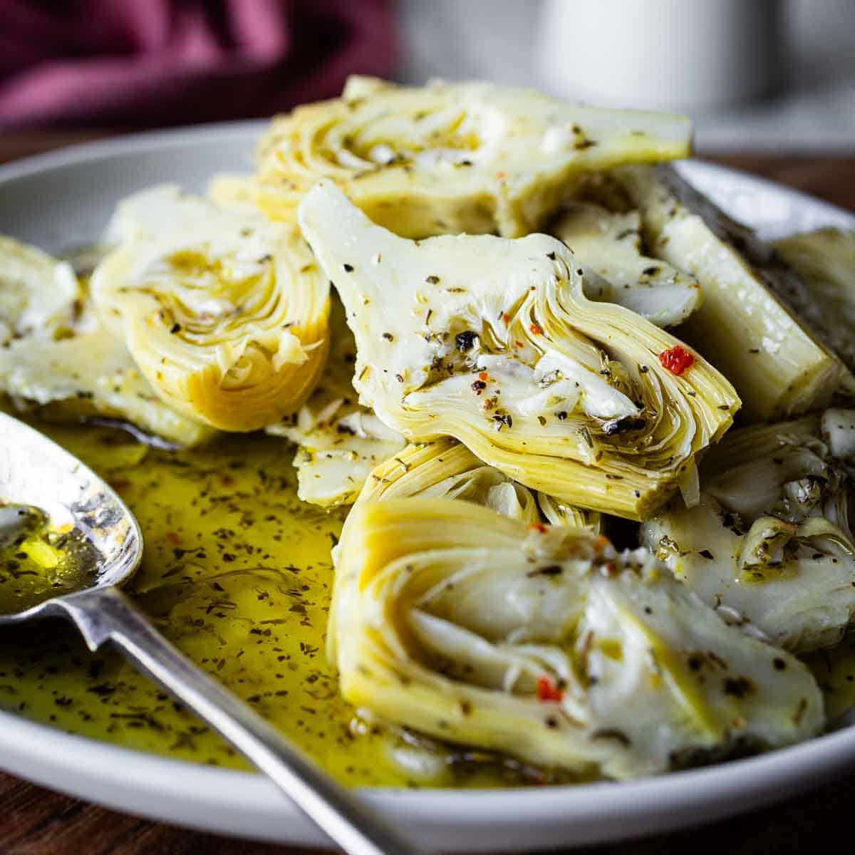 Close up of marinated artichokes plied onto a plate.