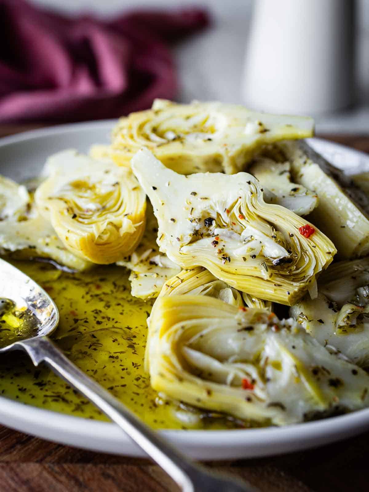 Close up of marinated artichokes plied onto a plate.