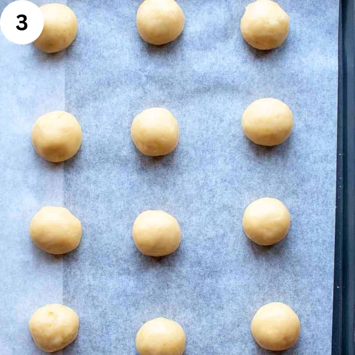 Cookie dough balls on a baking sheet.