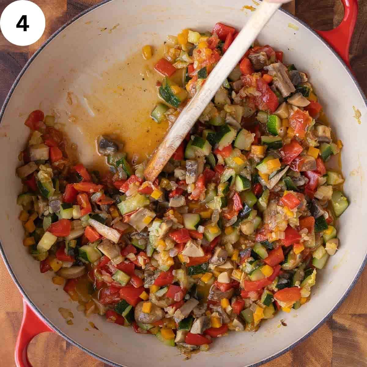 Stirring a cooked mixture of vegetables in a skillet.