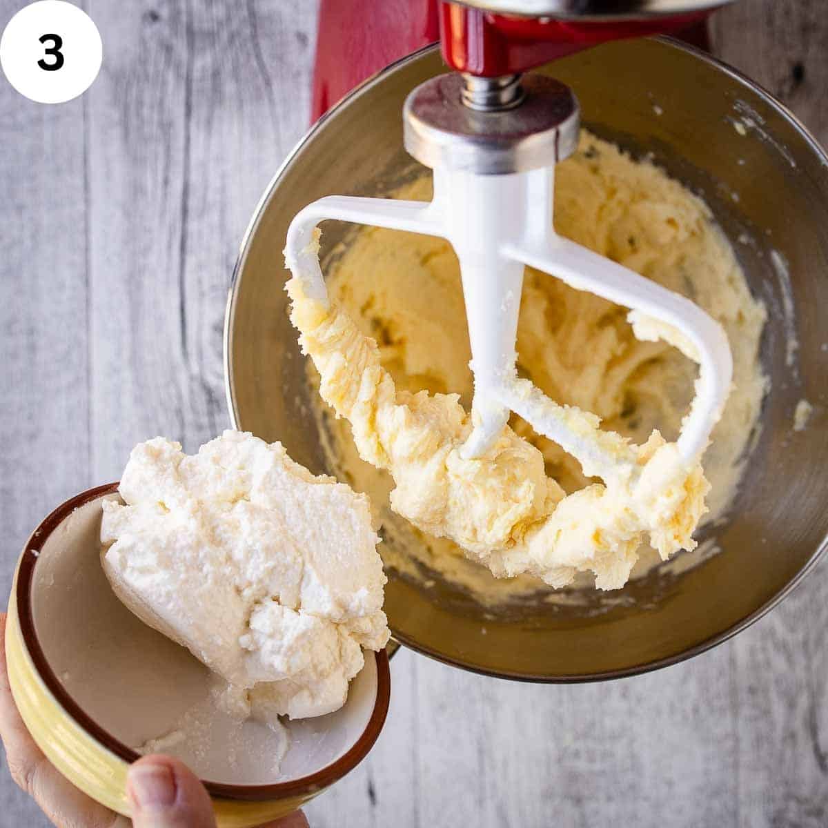 Adding ricotta cheese to creamy mixture in a stand mixer.