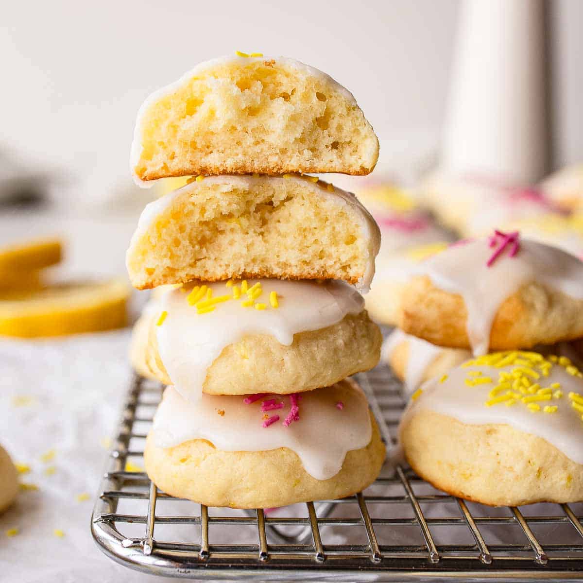 Lemony Ricotta Cookies piled up like a tower with two at the top broken in half.