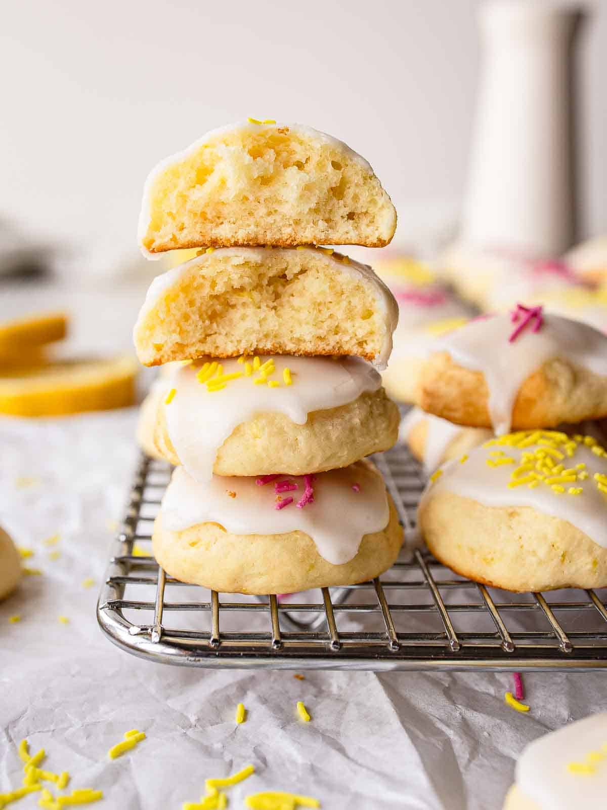Lemony Ricotta Cookies piled up like a tower with two at the top broken in half.