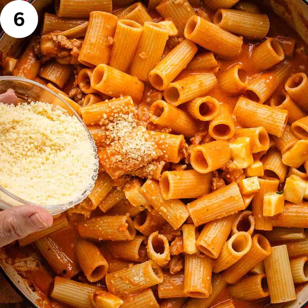 Sprinkling Parmesan cheese onto rigatoni pasta.