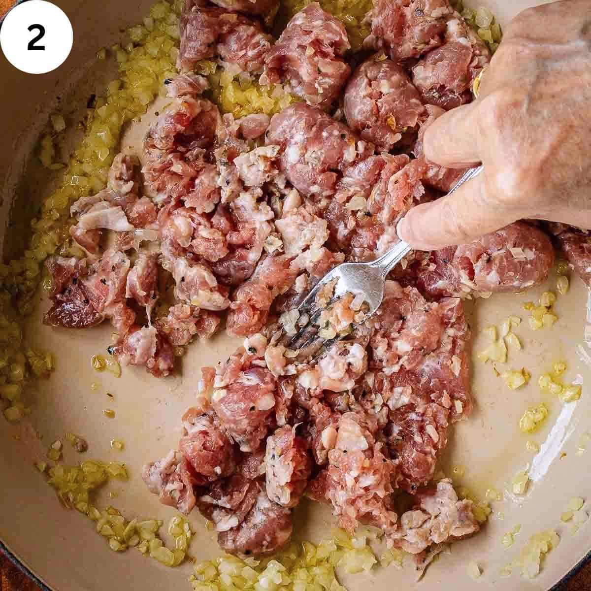 Using a fork to break up raw sausage in a frying pan.