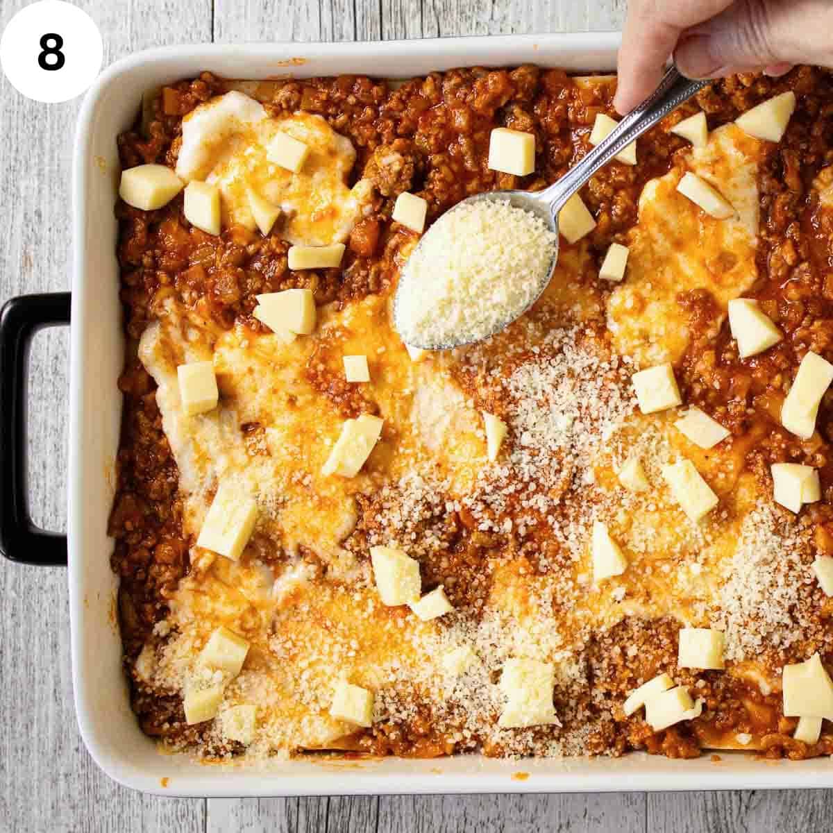 Sprinkling grated cheese over the top of a lasagna.