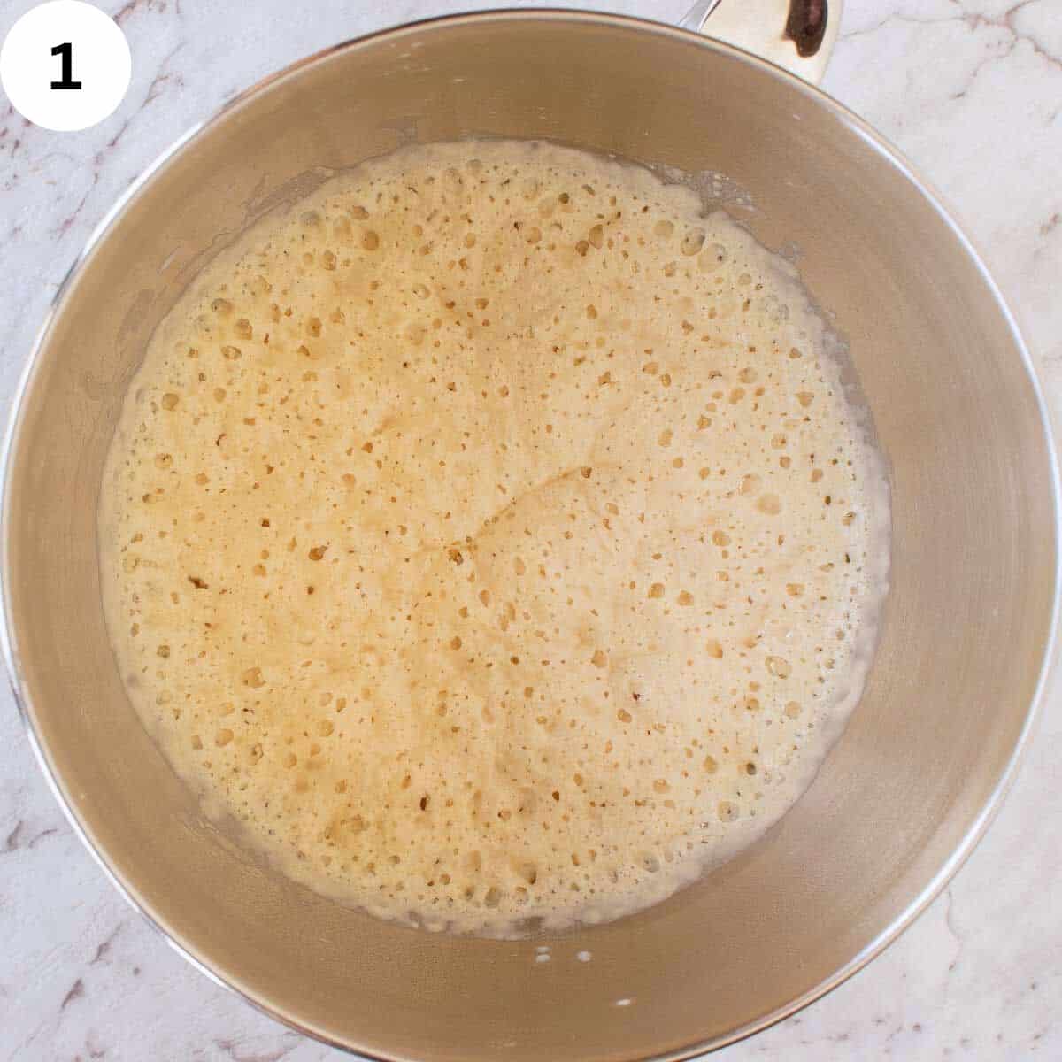 Pale yellow, bubbly batter in a stainless steel bowl. 