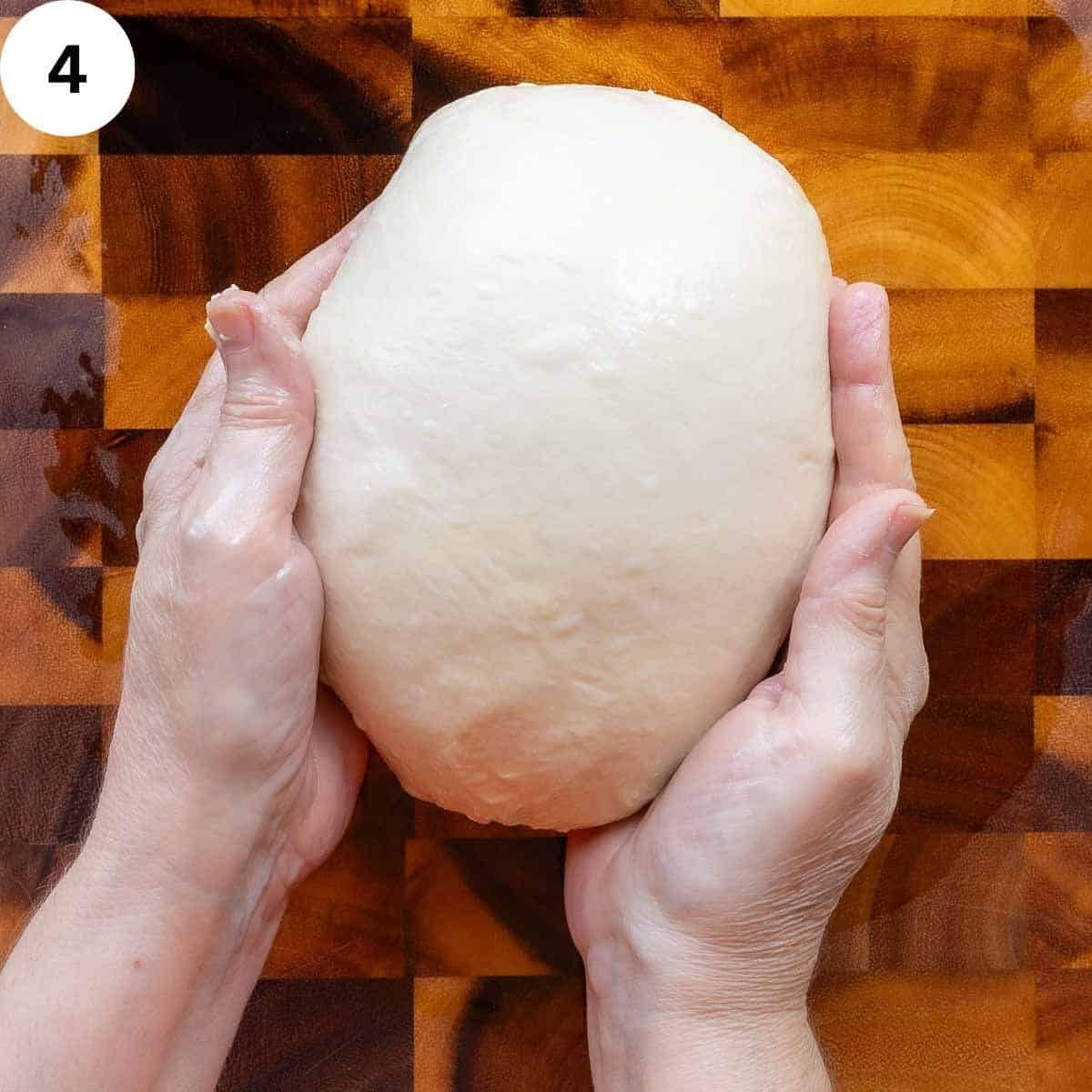 Hands forming yeast dough into a ball.