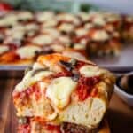 Two squares of Anchovy Pizza stacked on top of one another.