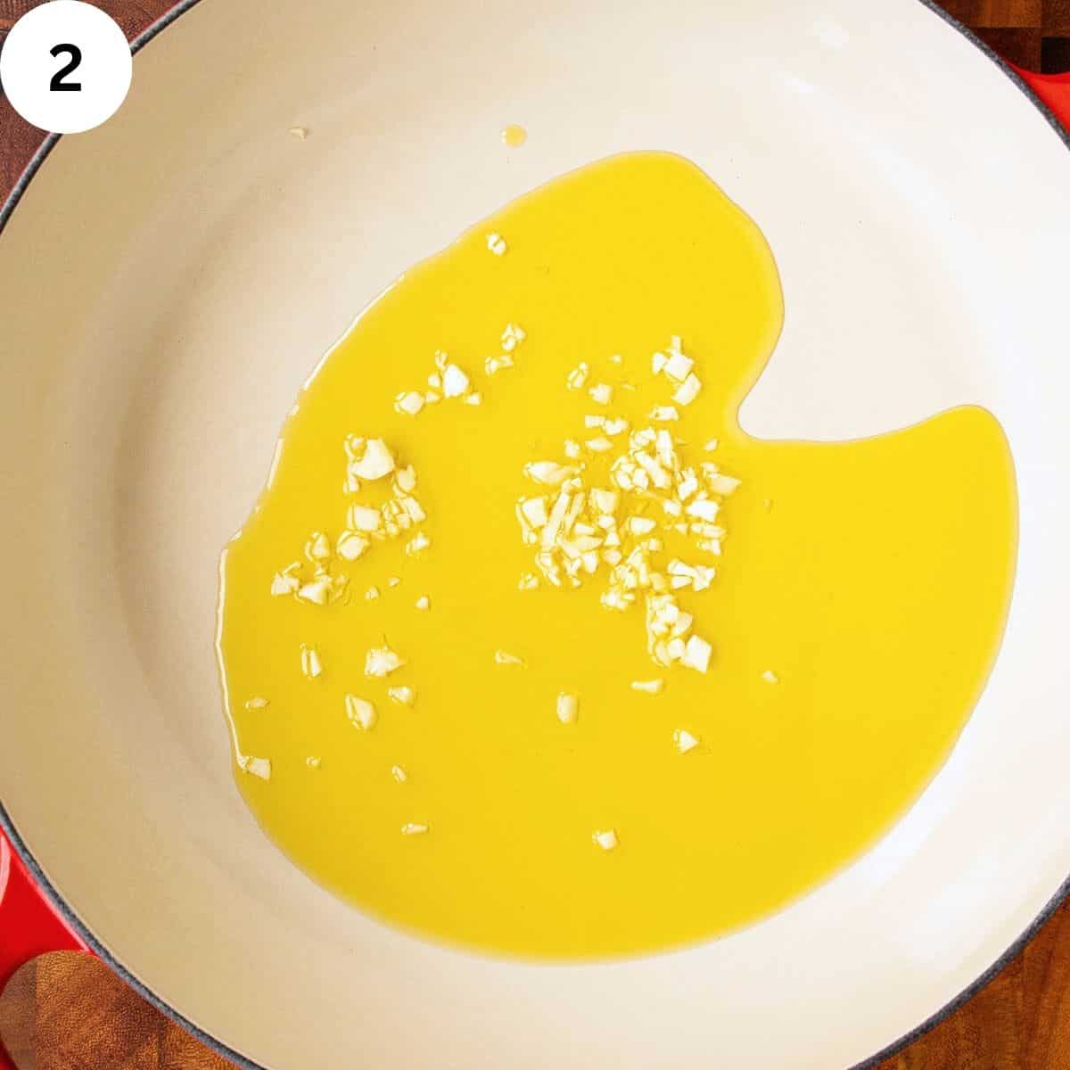 Olive oil in a pan with chopped garlic viewed from above.