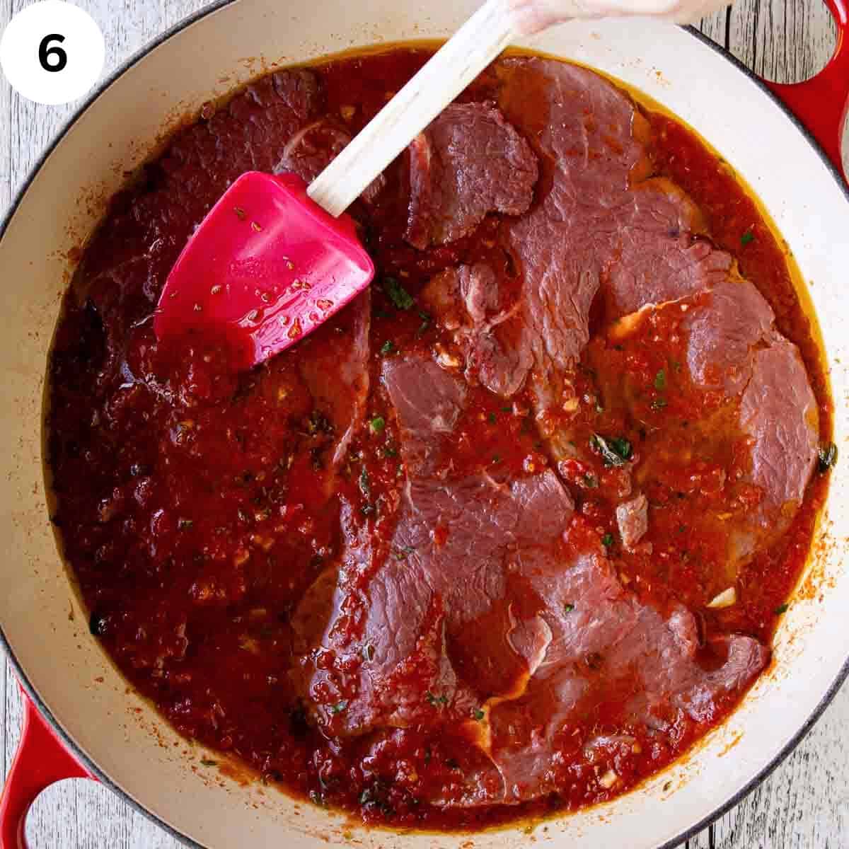 Spooning  tomato puree onto steaks in a pan.