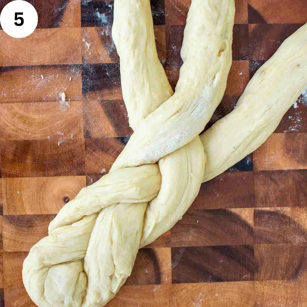 Three strands of dough in the process of being braided.