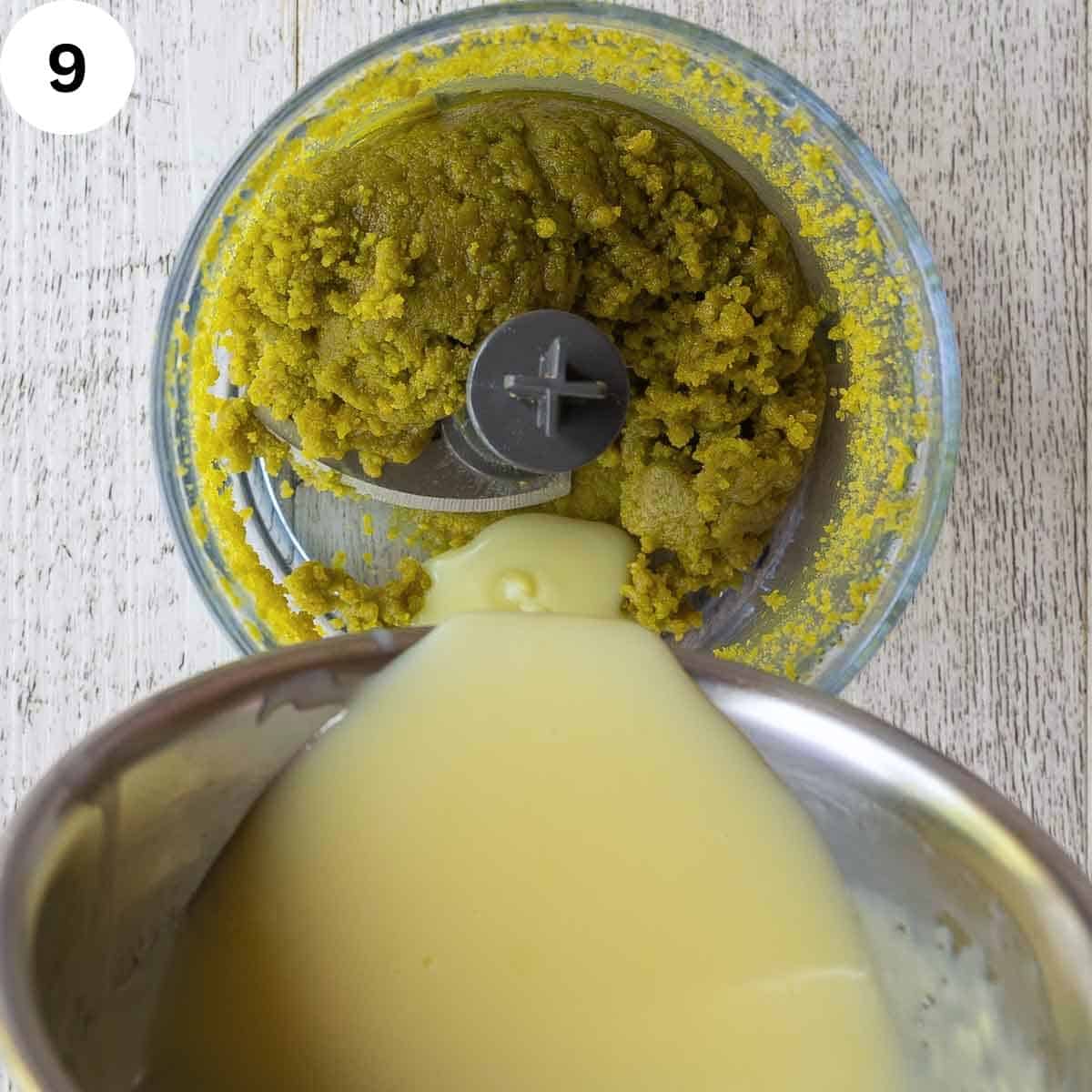 Pouring creamy liquid from saucepan into food processor of ground pistachios.