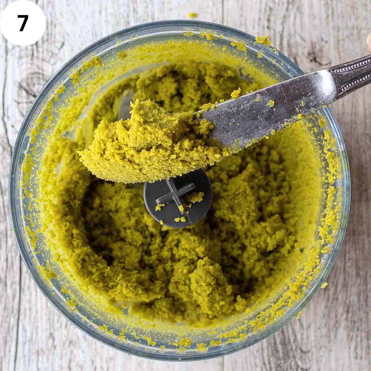 A butter knife piled up with very finely ground pistachio nuts.