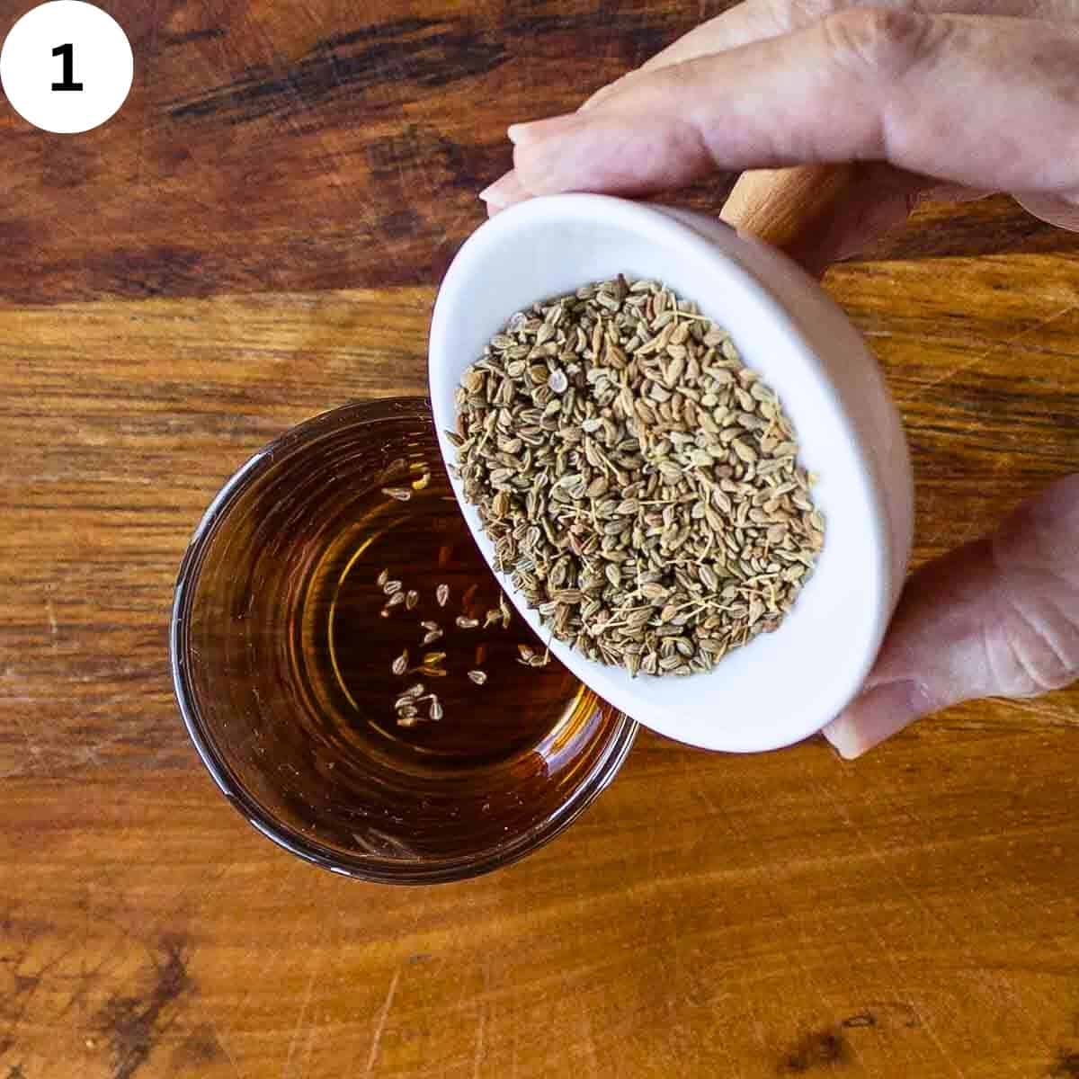 Pouring anise seeds into rum.