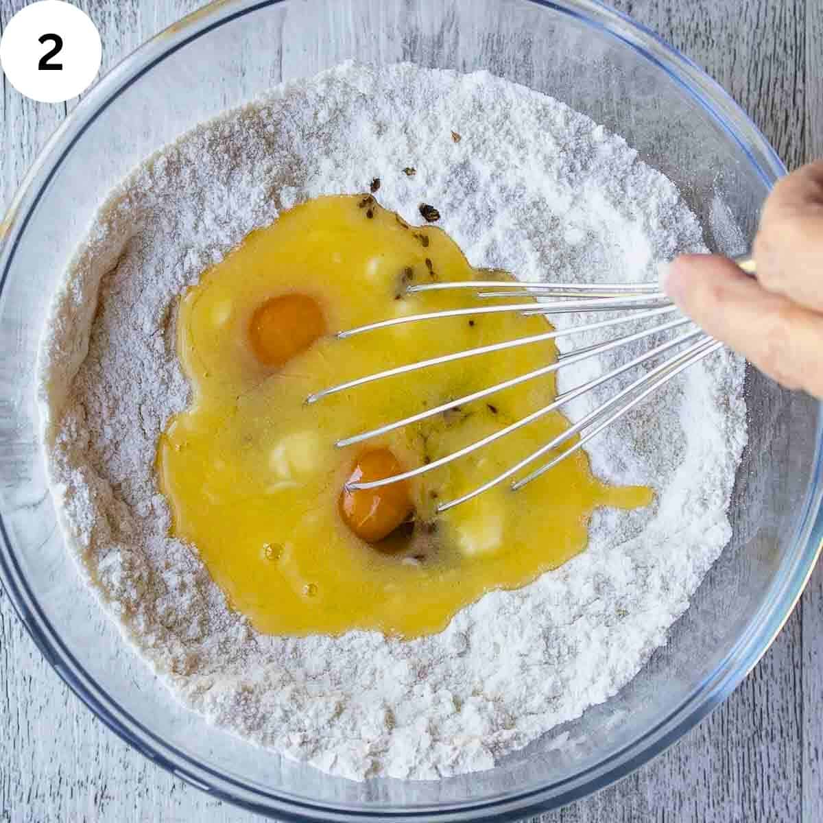 Whisking eggs and melted butter into flour.
