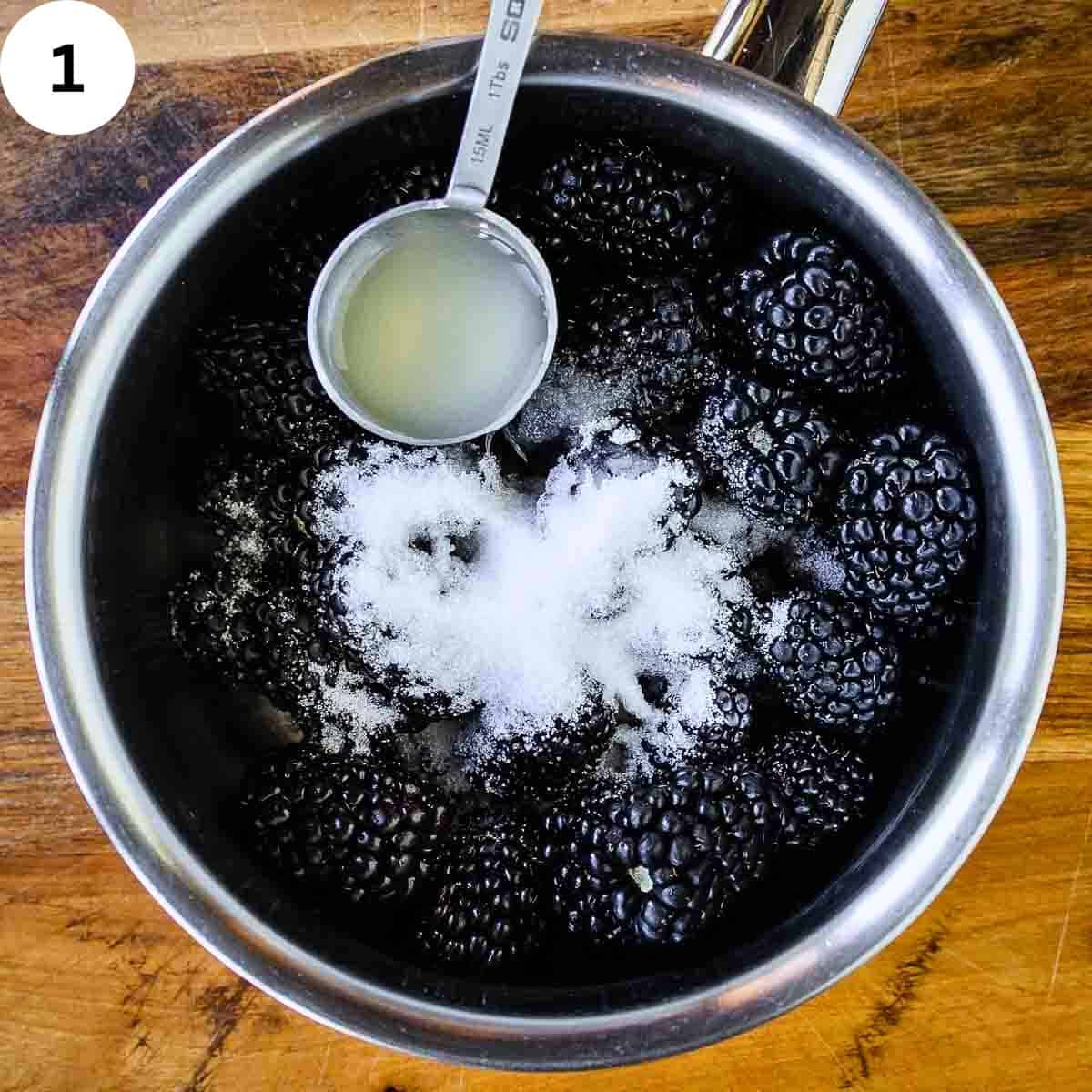 Lemon juice being spooned into a saucepan of blackberries and sugar.