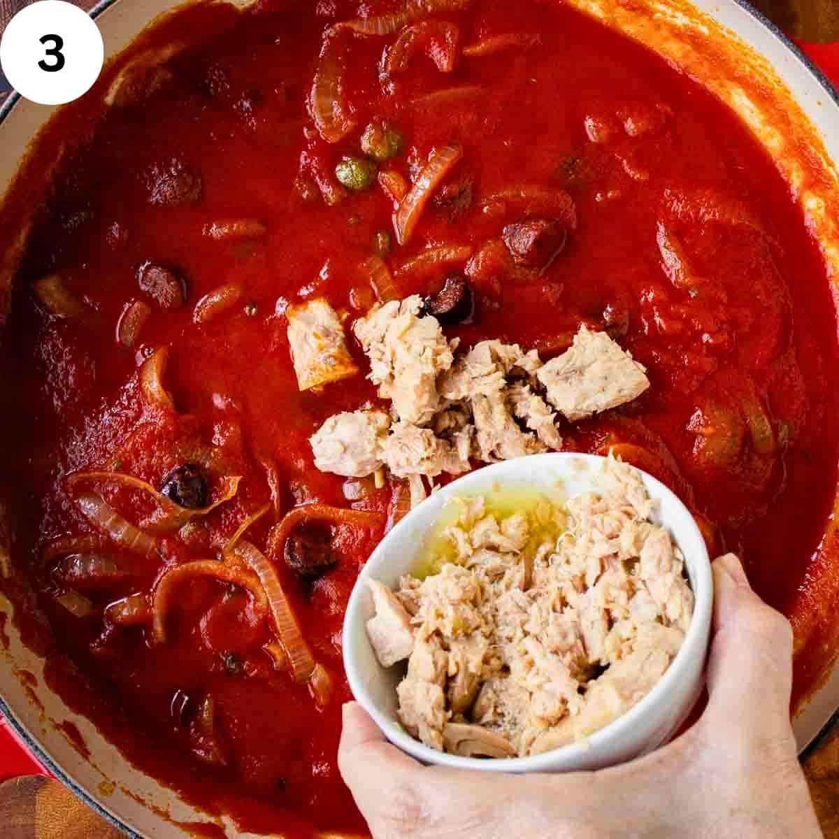Canned tuna being added to tomato pasta sauce.