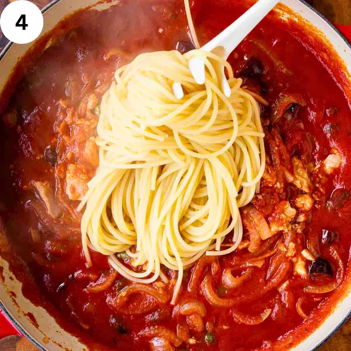 Spaghetti being added to tuna tomato sauce.