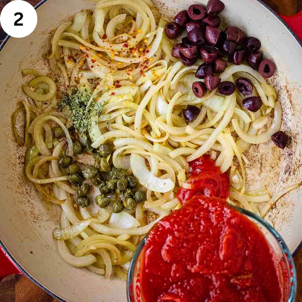 Tomato puree being added to pan of fried onions, olives and capers.