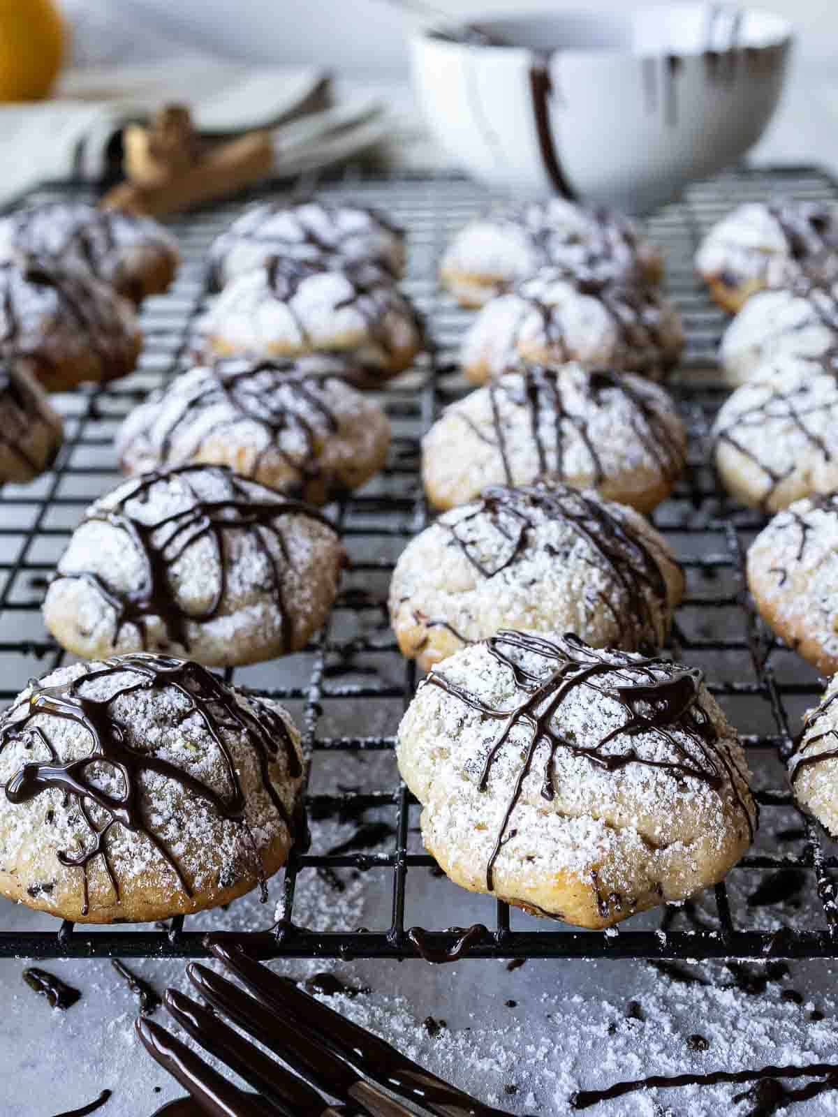 Chocolate drizzled cannoli cookies on a cooling rack.