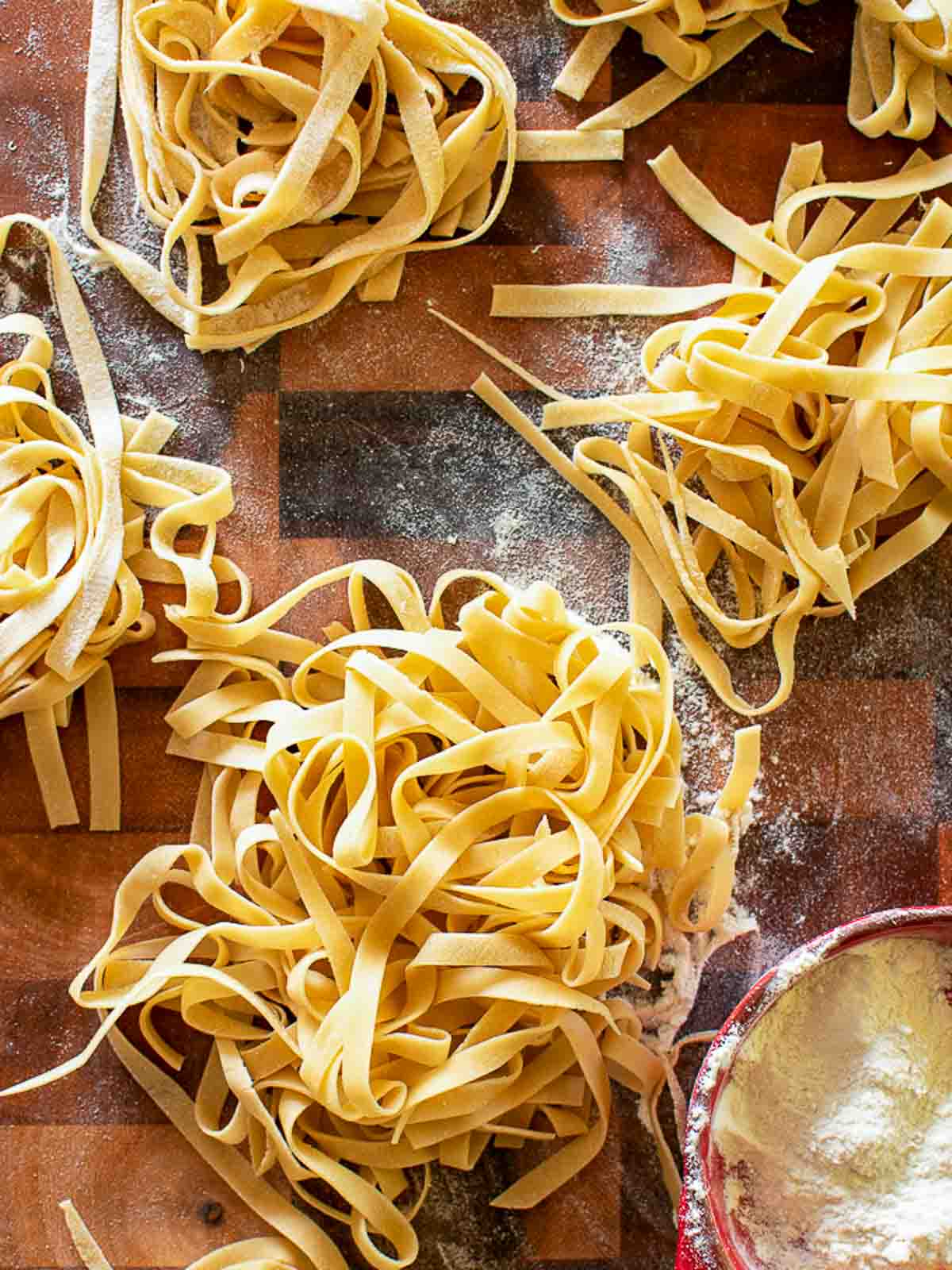 Making fresh pasta a home requires only two ingredients - flour and eggs. Learn how to make your own egg pasta with this step by step recipe. #homemade #homemadepasta #eggpasta #italianrecipe #pastarecipe Homemade tagliatelle pasta nests overhead view.