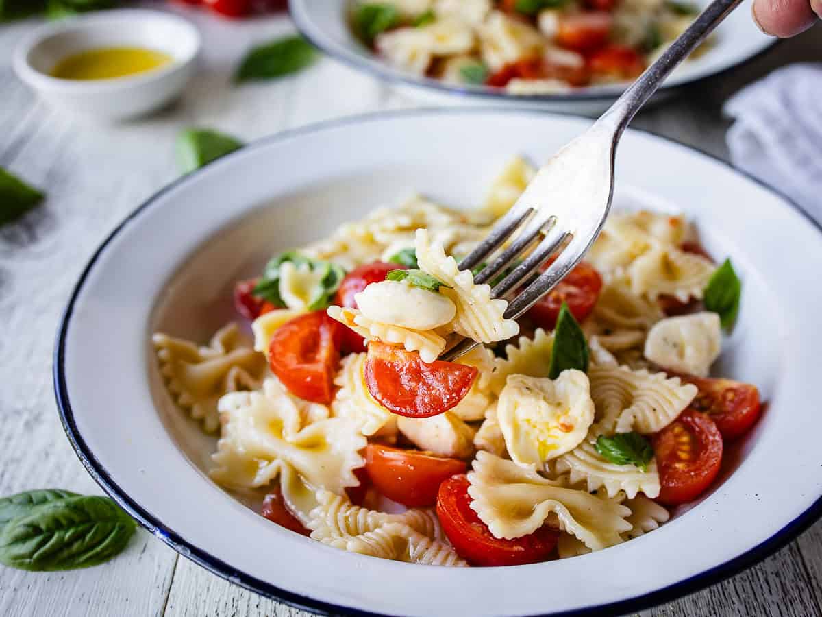 Close up of pasta salad with tomatoes and mozzarella.