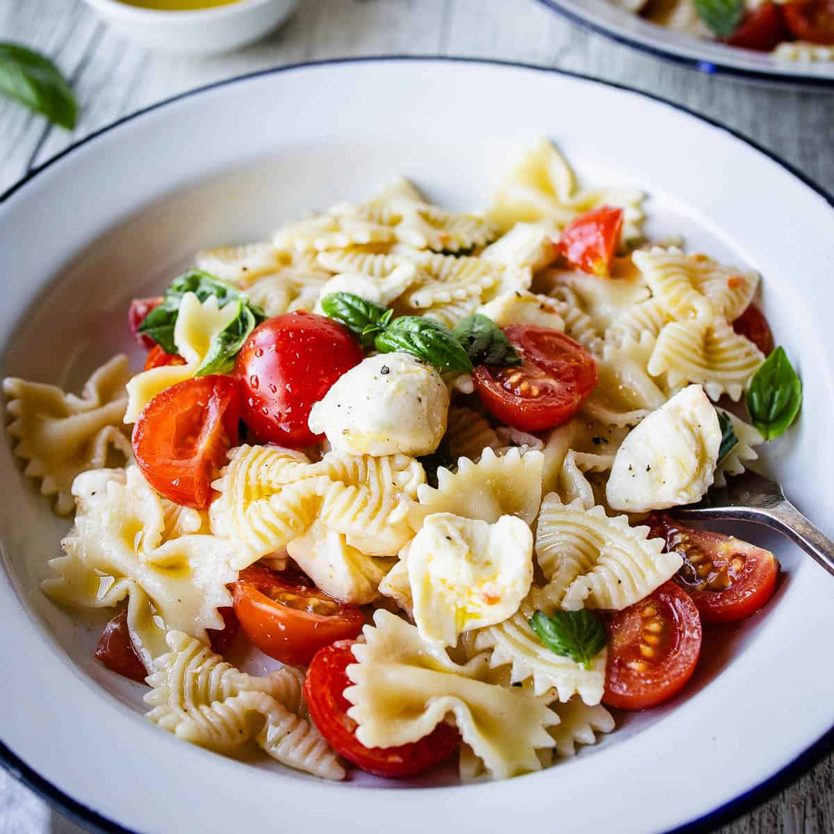 Caprese Pasta Salad in a bowl with another bowl in the background.