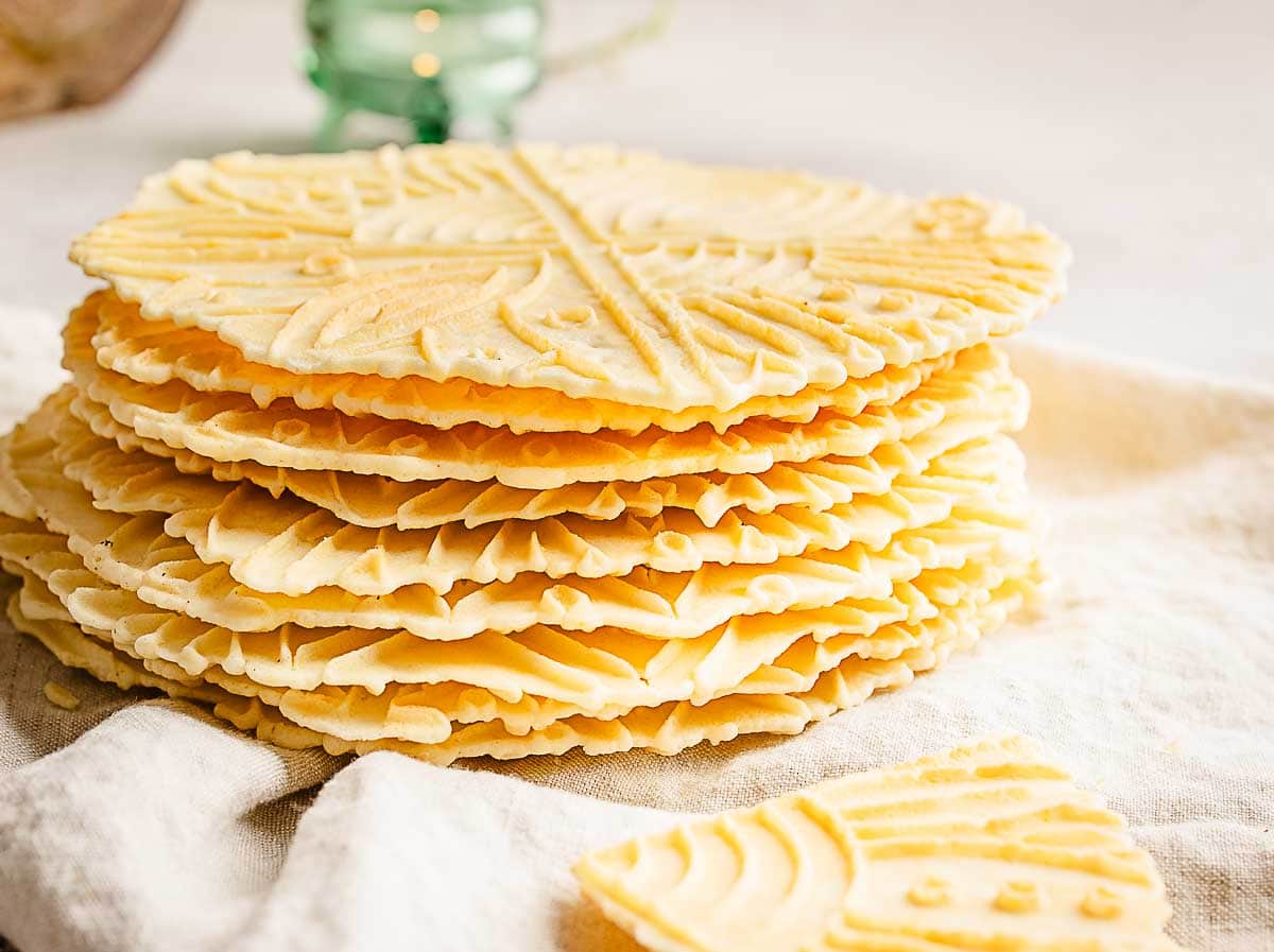 Pizzelle cookies stack with a broken one in the front.