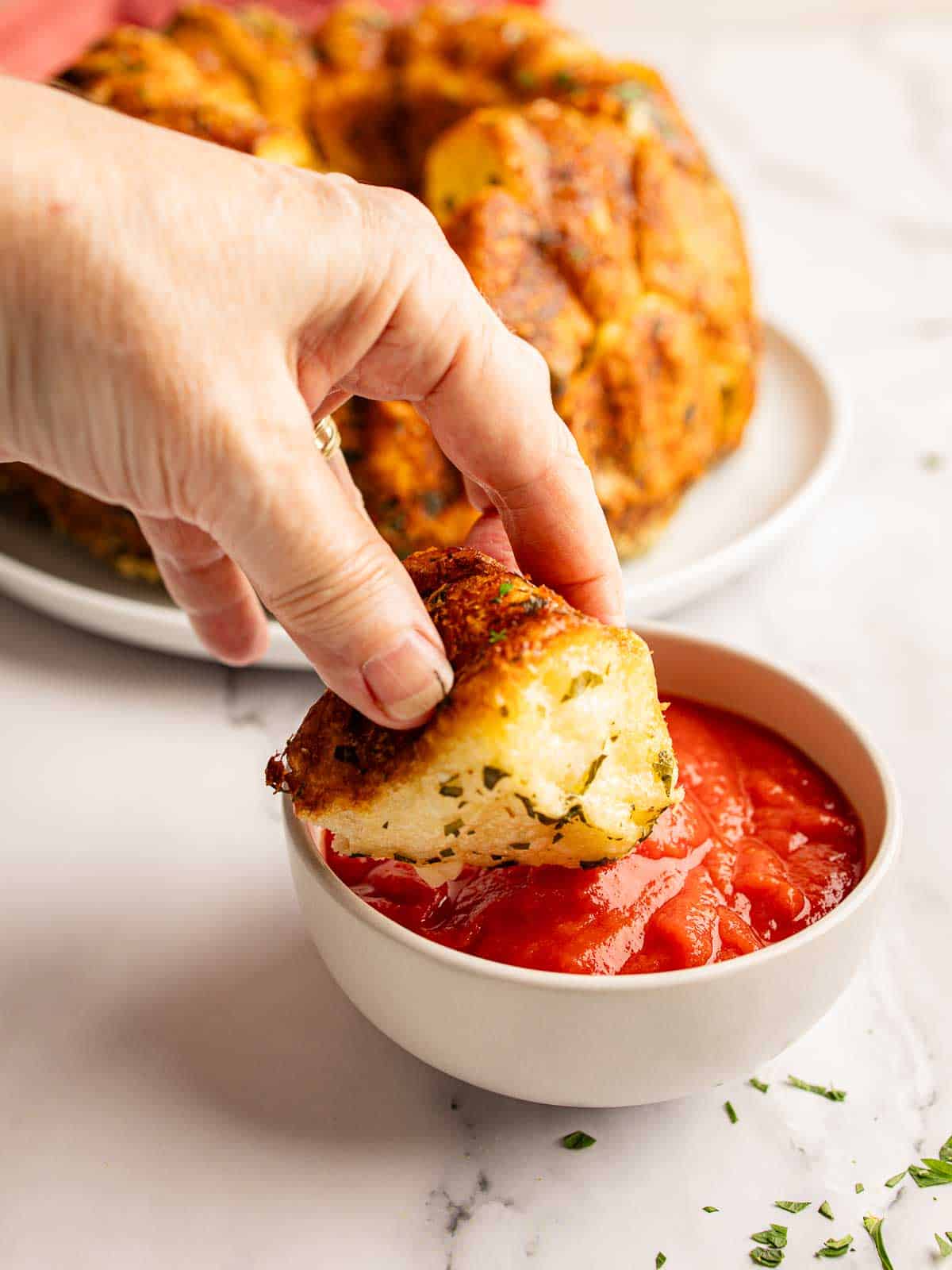 A piece of homemade garlic bread being dipped into tomato sauce