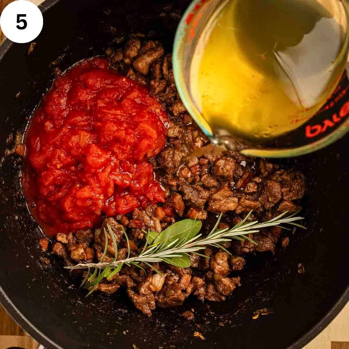 Pouring chicken stock into ingredients for a ragu.