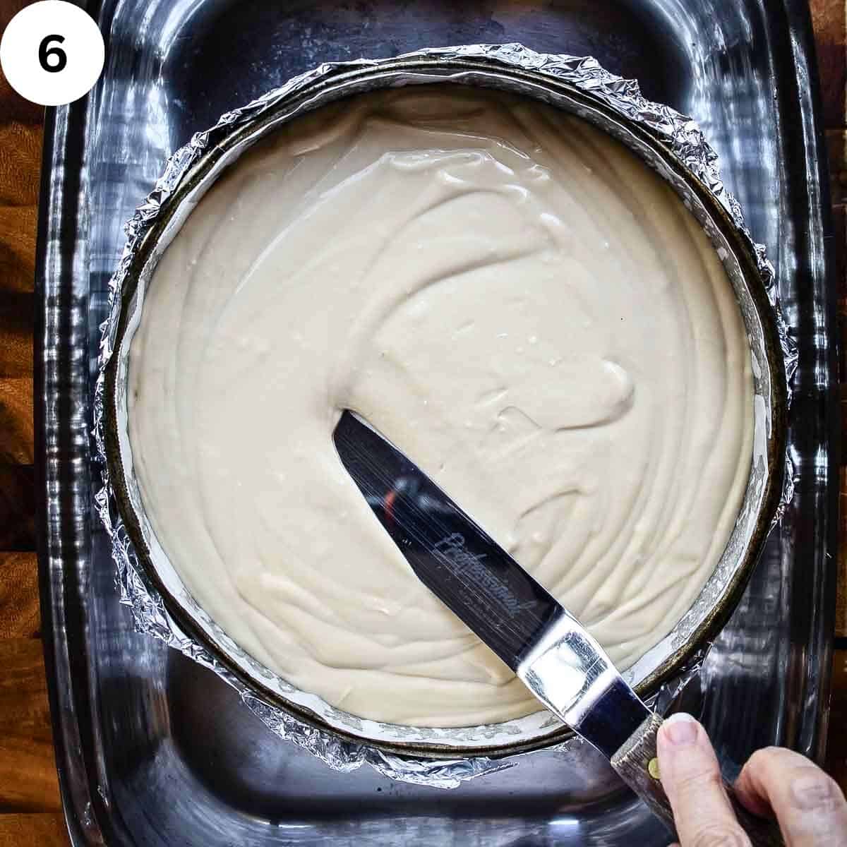 Smoothing the top of creamy cheesecake filling in a pan.