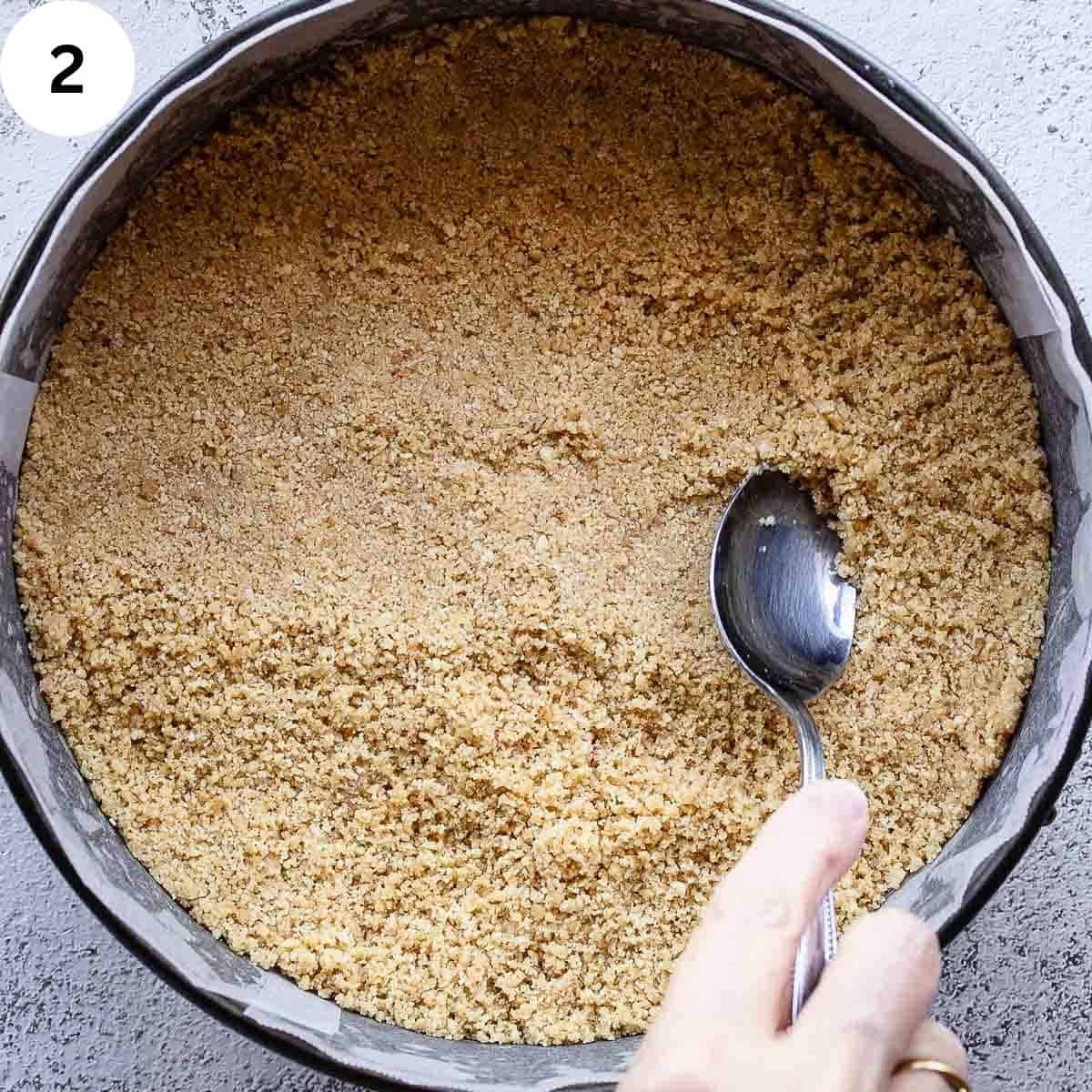 Pressing cookie crumbs into a springform pan.