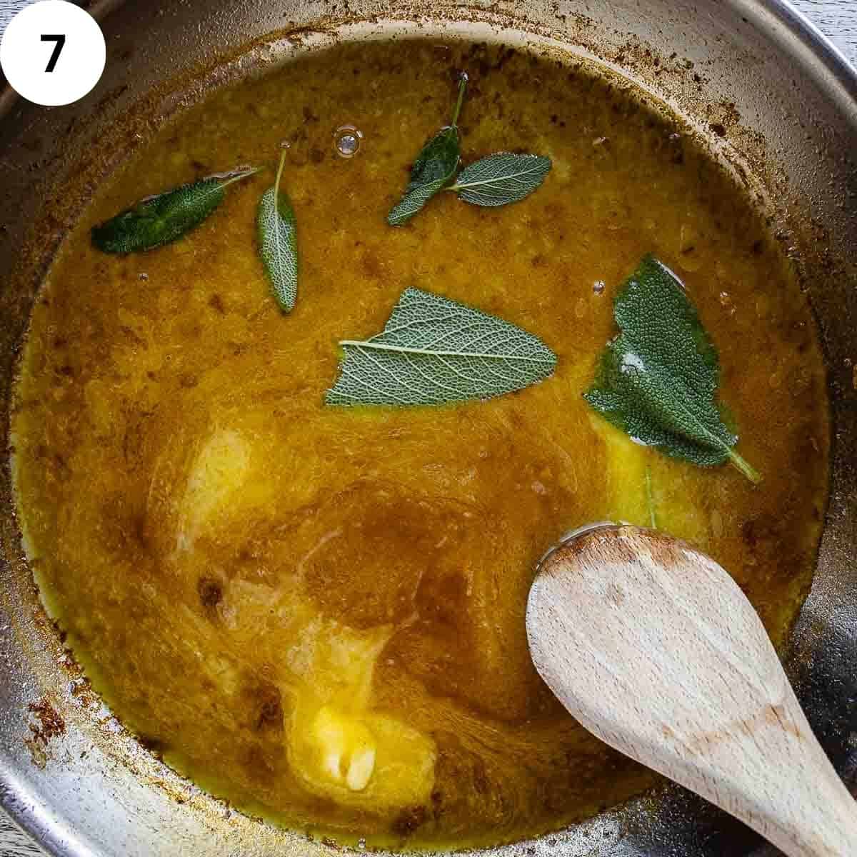 Sage leaves and butter being stirred into a sauce in a frying pan.