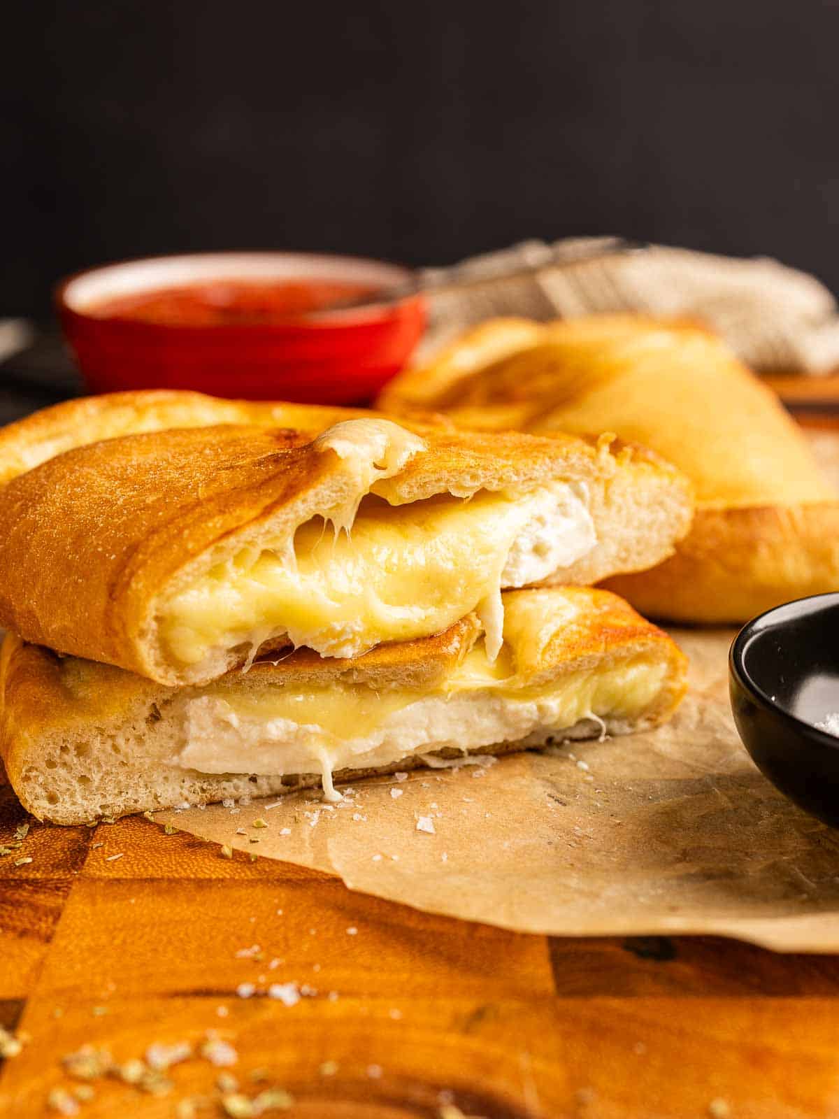 Cheese calzone cut in half and place one on top the the other half showing cheese oozing.