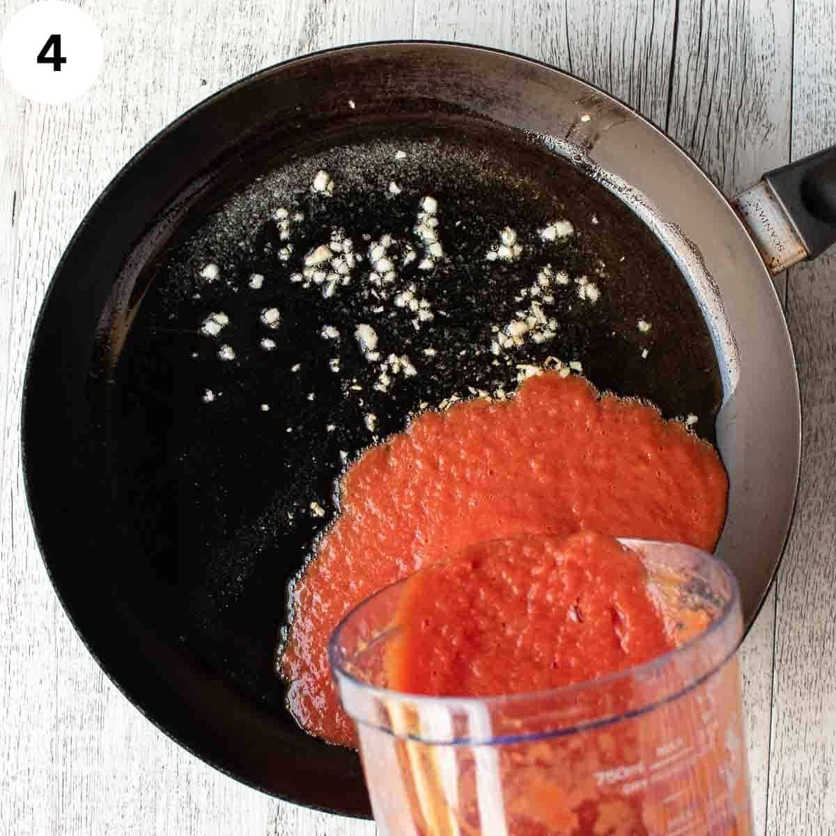 Pour pureed tomato into a skillet onto chopped garlic and oil.