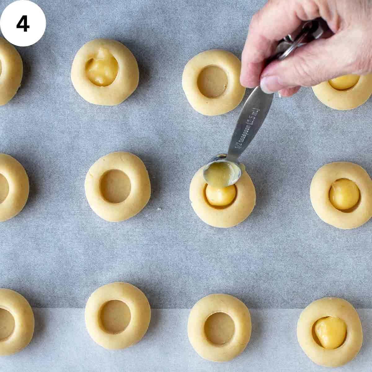 Filling indentation in dough balls with lemon curd.