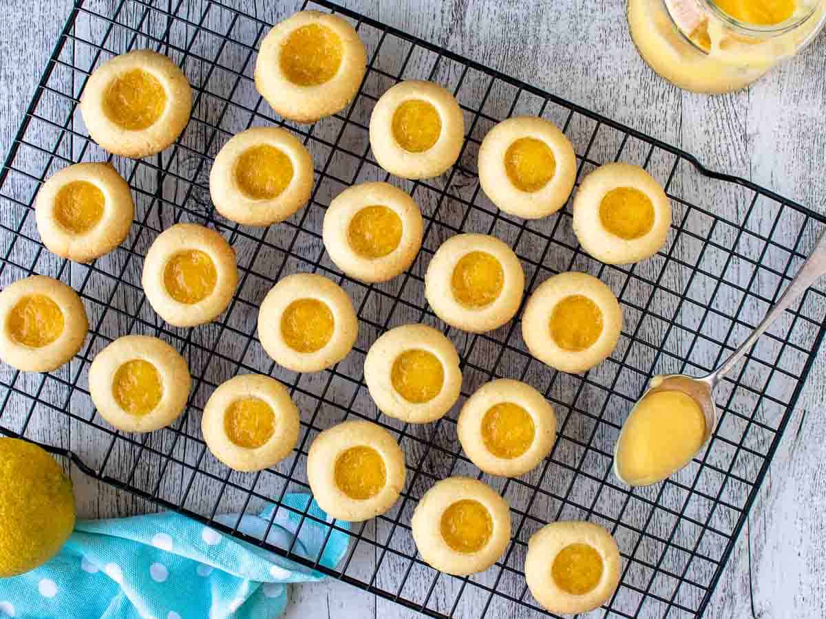 Overhead view of cookies with lemon curd centres on black wire rack.
