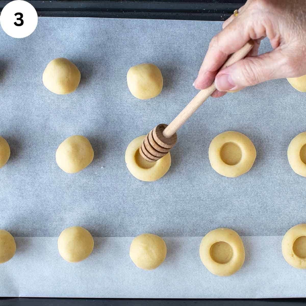 Pressing a wooden honey stick into dough balls to create a indentation.