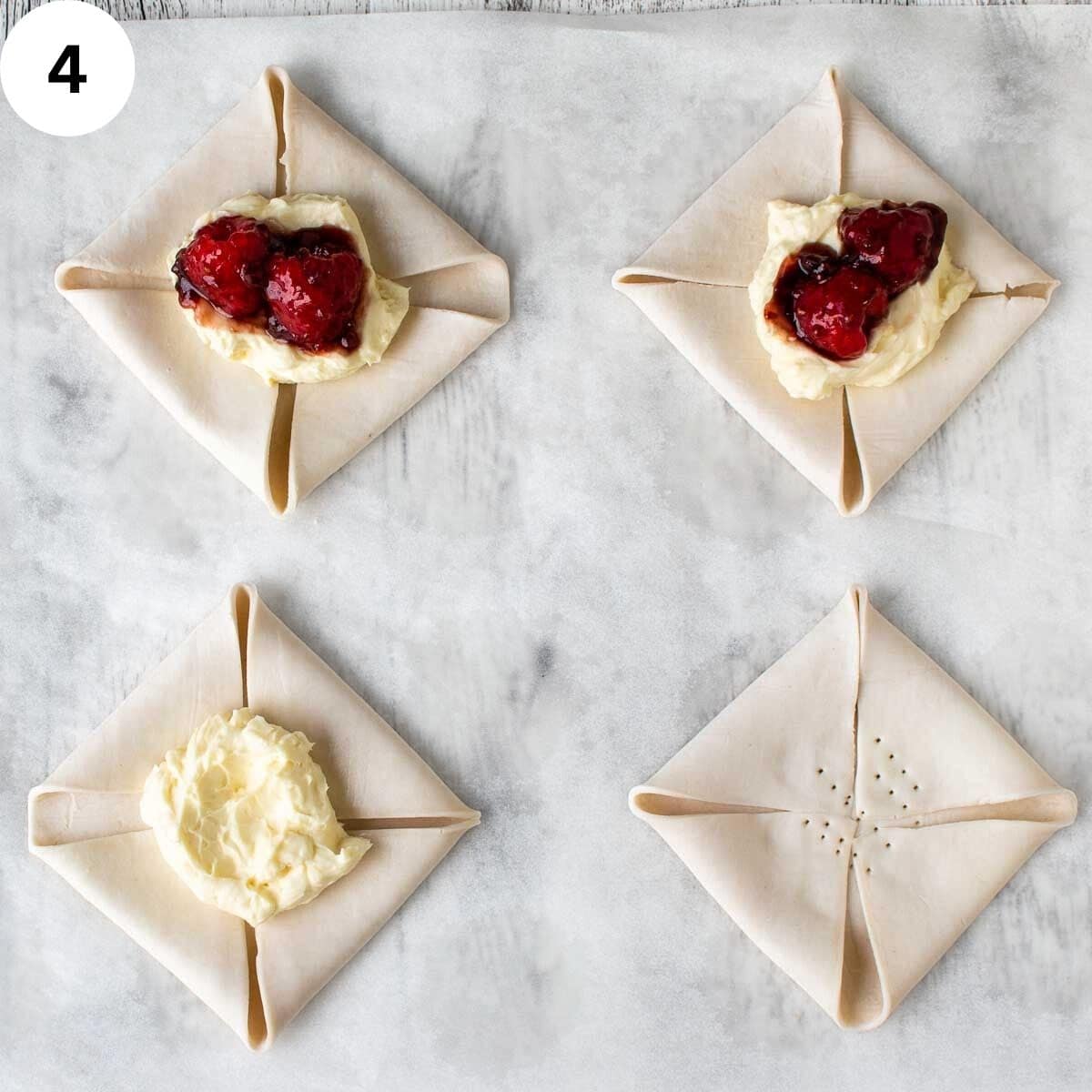 Folded squares of uncooked pastry with creamy topping and raspberries and jam in the middle of each.
